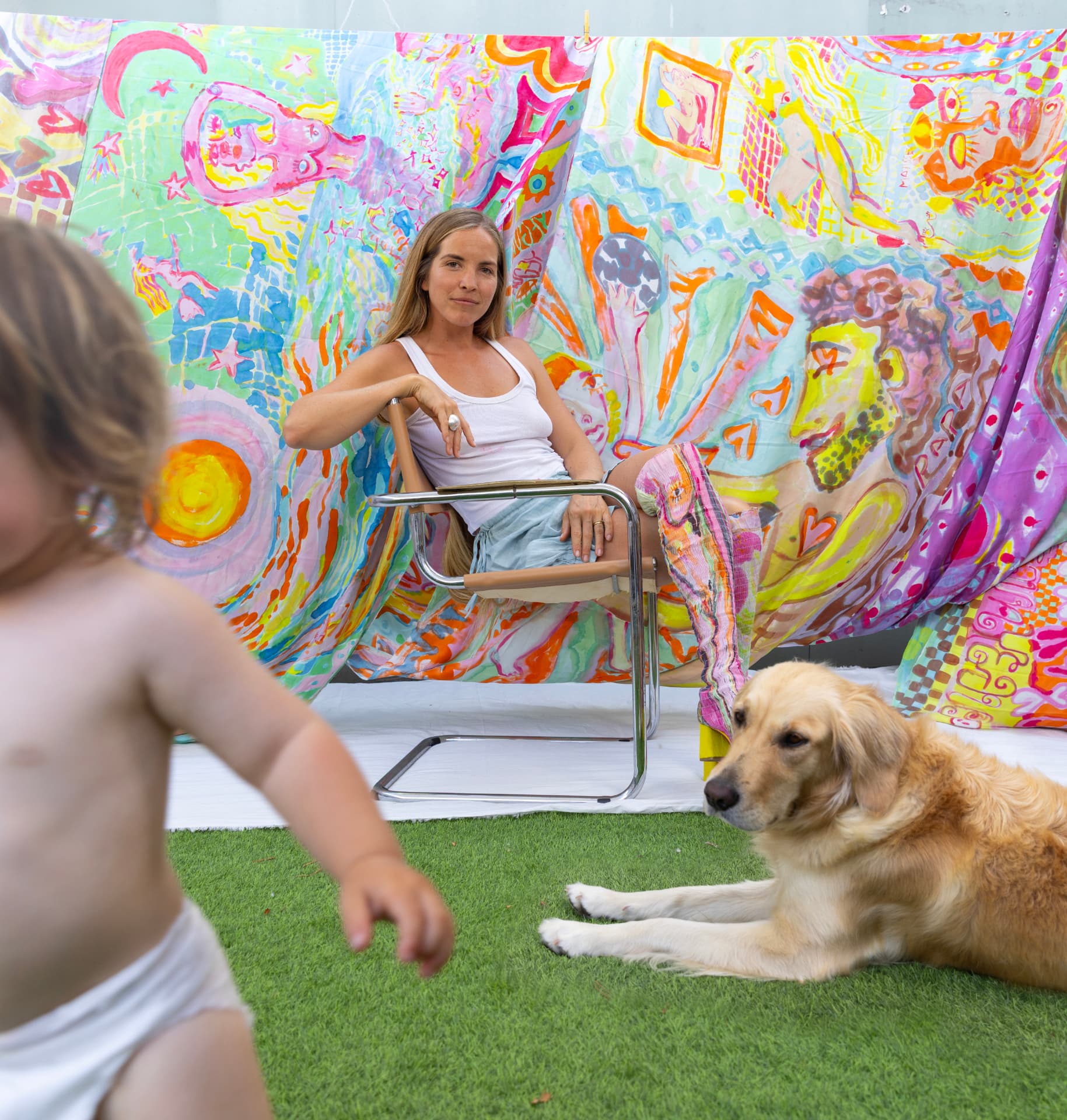 Florencia Montefalcone with her child in front of hand-painted silk textiles